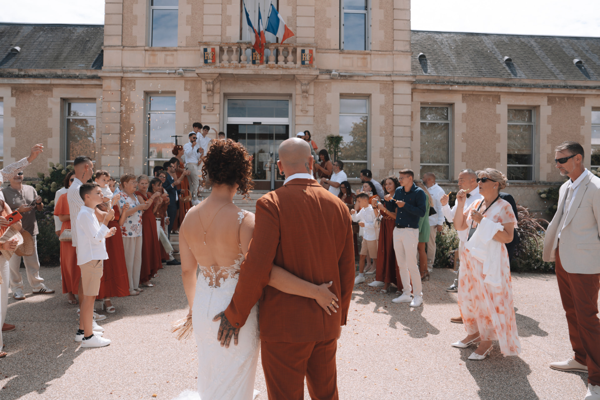 Les mariés face aux invités qui soufflent des bulles sur le parvis de la mairie